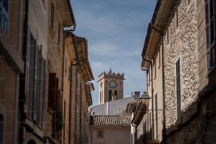 a narrow street with a clock tower in the distance