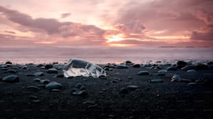 uma garrafa de vidro quebrada sentada em cima de uma praia de areia