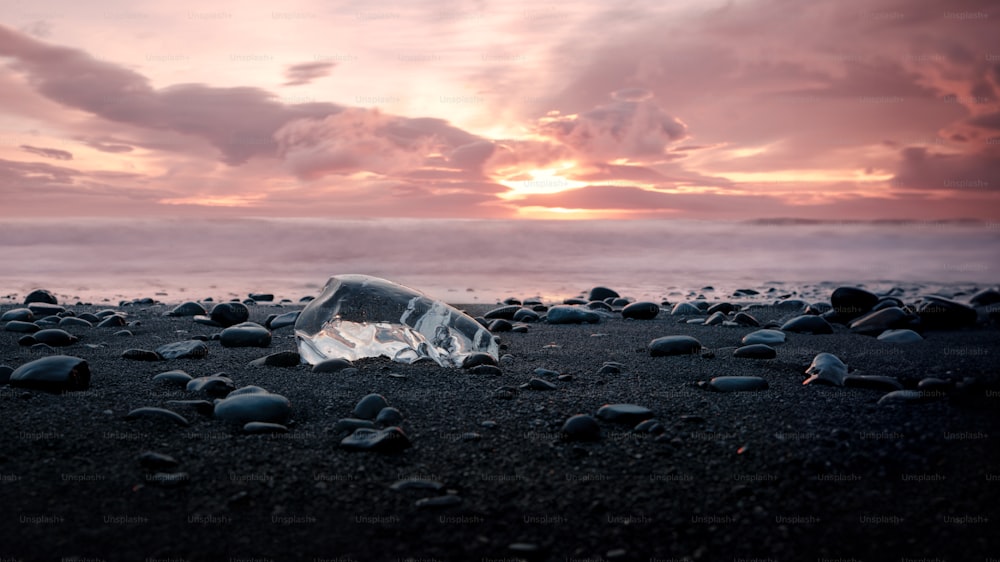 a broken glass bottle sitting on top of a sandy beach