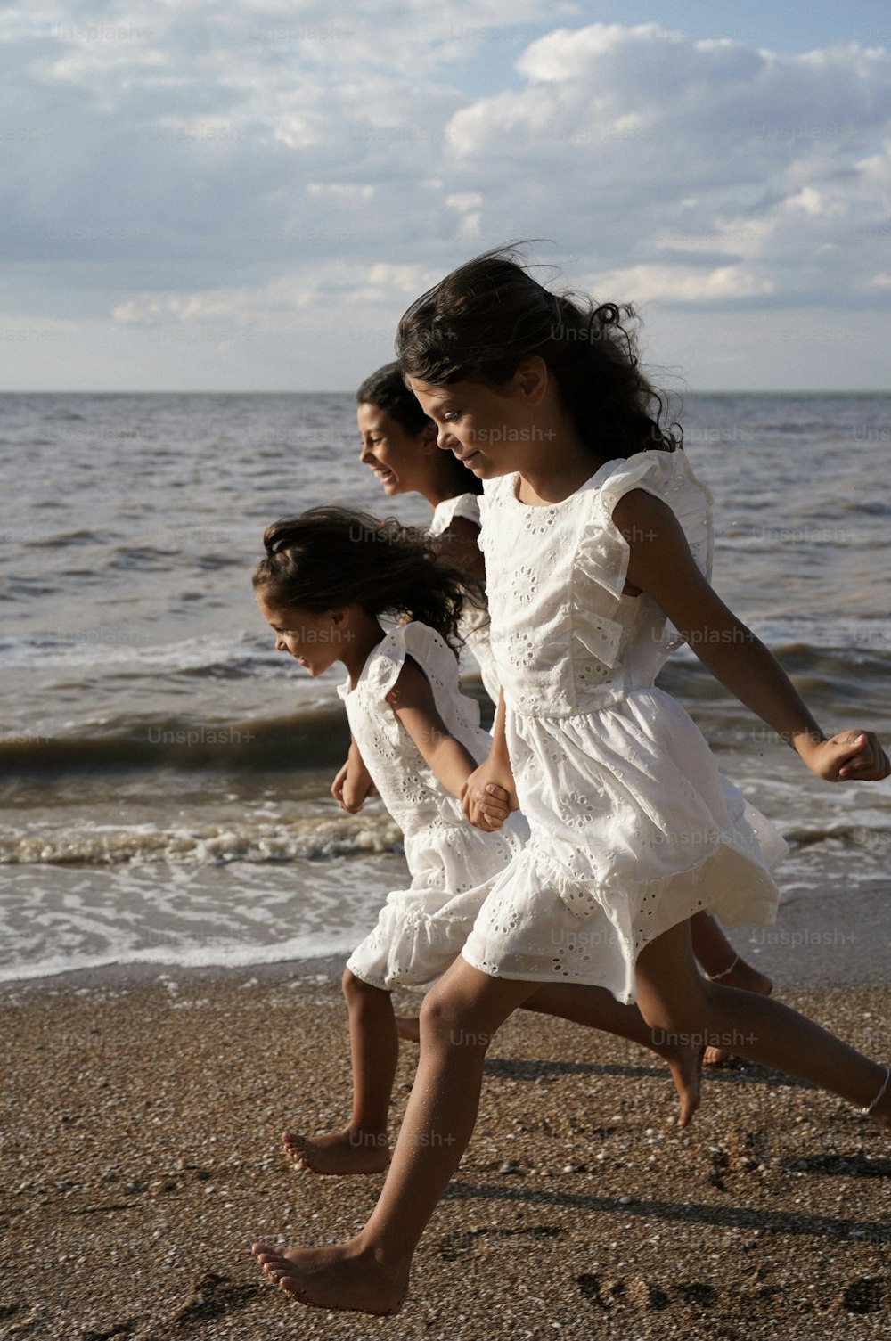 three little girls running on the beach together