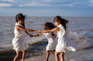 drei kleine Mädchen, die am Strand im Wasser spielen