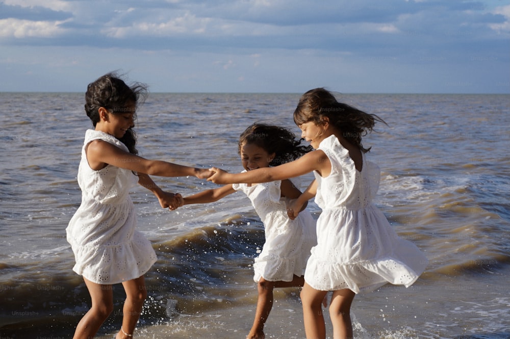 three little girls playing in the water at the beach