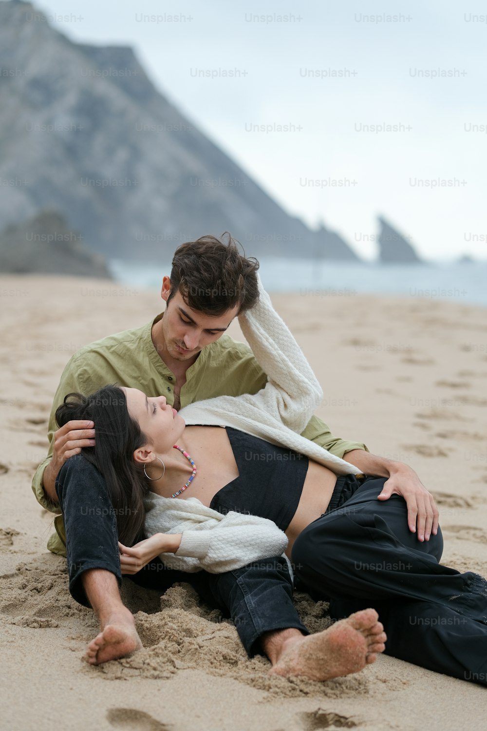 a man and a woman laying on the beach