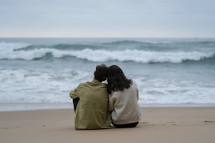 Un par de personas sentadas en la cima de una playa de arena