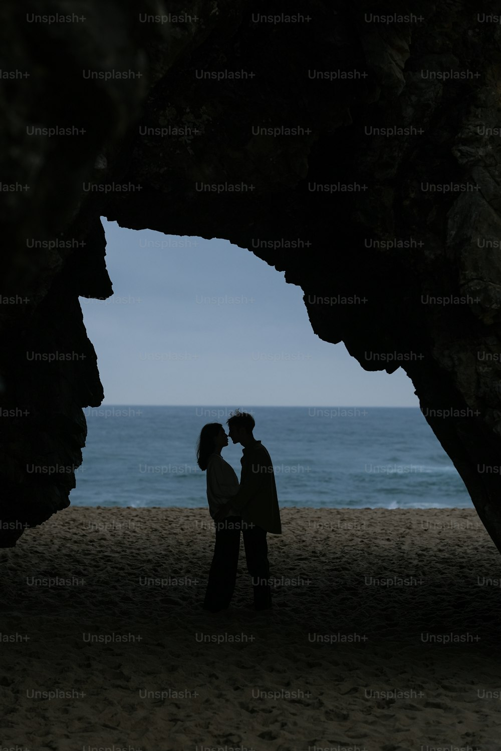 해변의 동굴 아래에 서 있는 남자와 여자