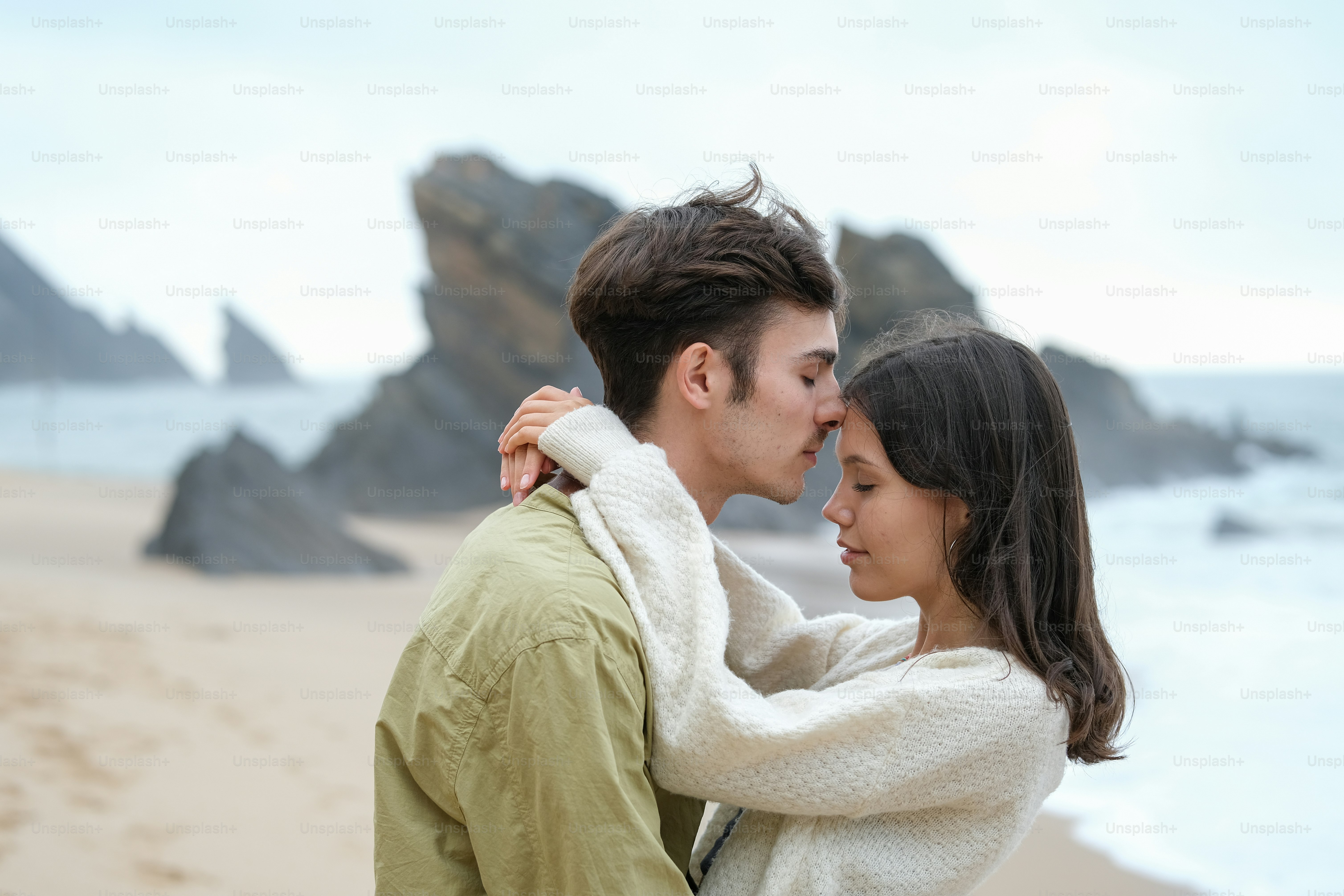 Un hombre y una mujer parados uno al lado del otro en una playa