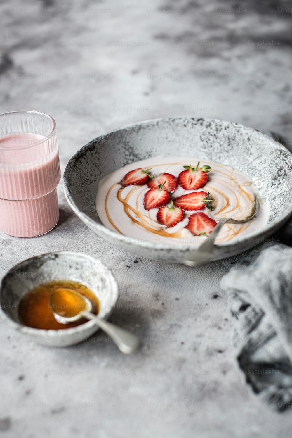 a bowl of strawberries next to a glass of orange juice