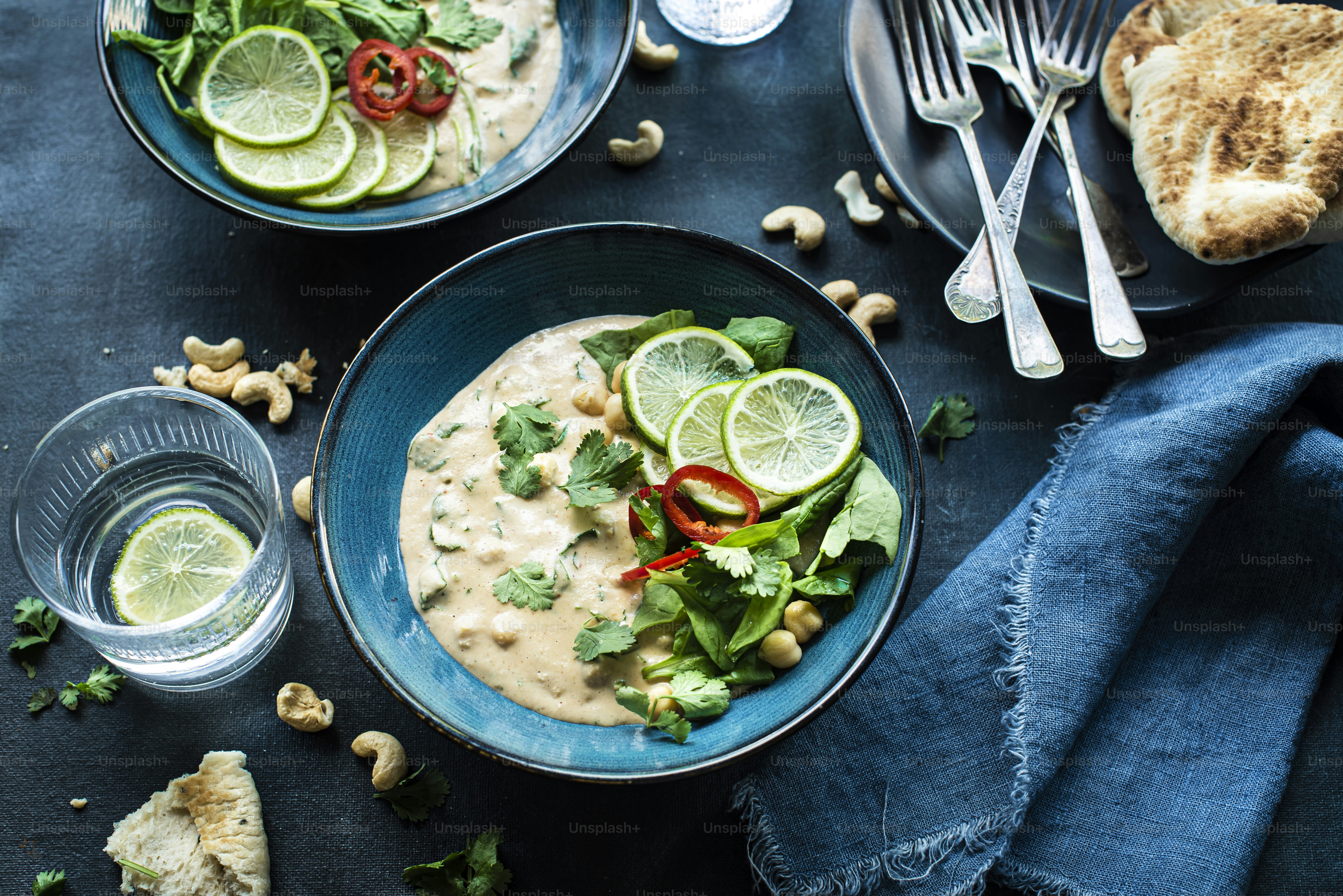 two bowls of soup with limes, cashews, cashews,