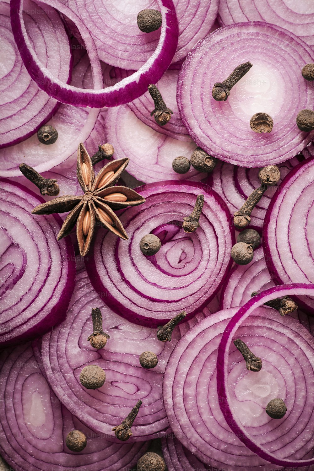 a pile of sliced red onions with anise on top