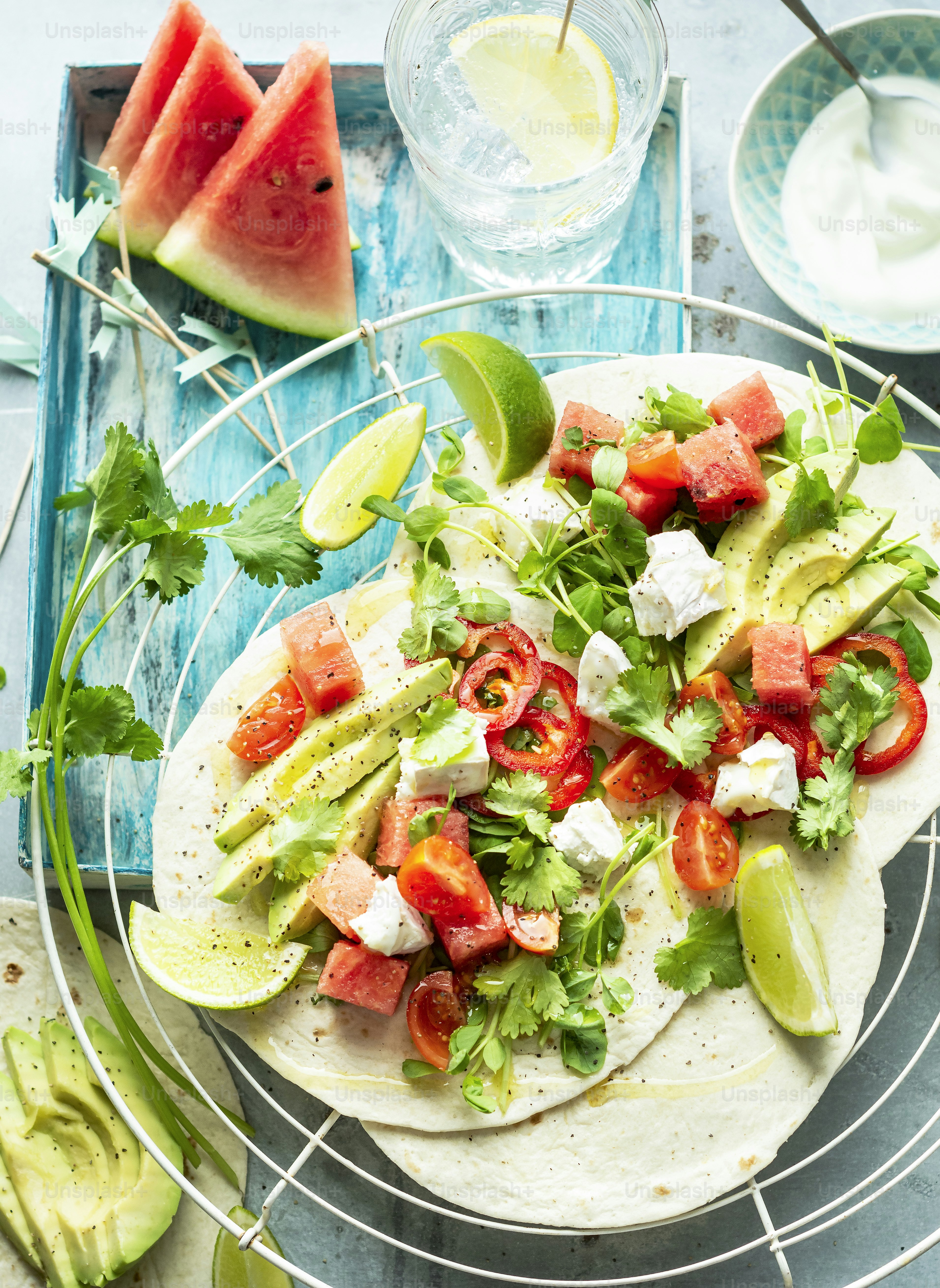 a plate of food with watermelon, lettuce, tomatoes, and