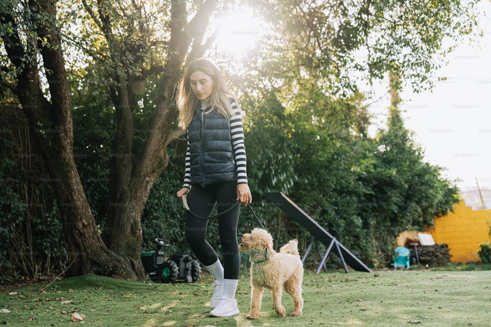 공원에서 작은 개를 산책시키는 여자