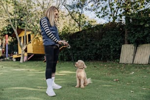 a woman holding a dog on a leash in a yard