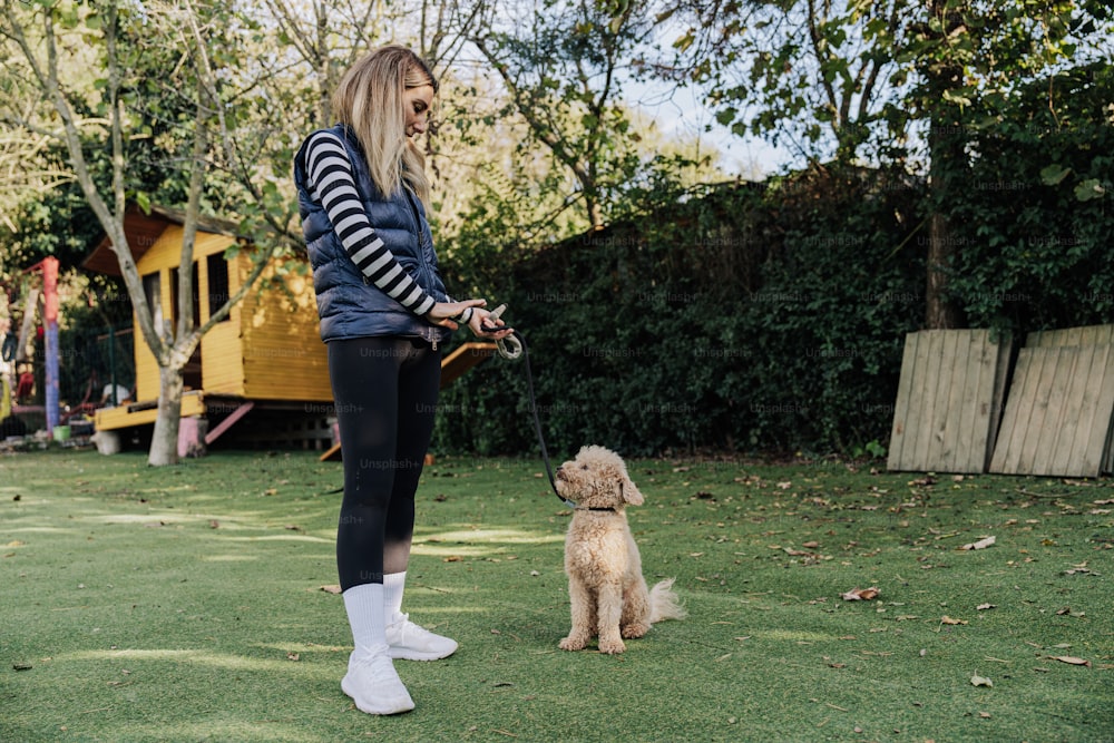 a woman holding a dog on a leash in a yard