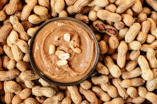 a bowl of peanut butter surrounded by peanuts