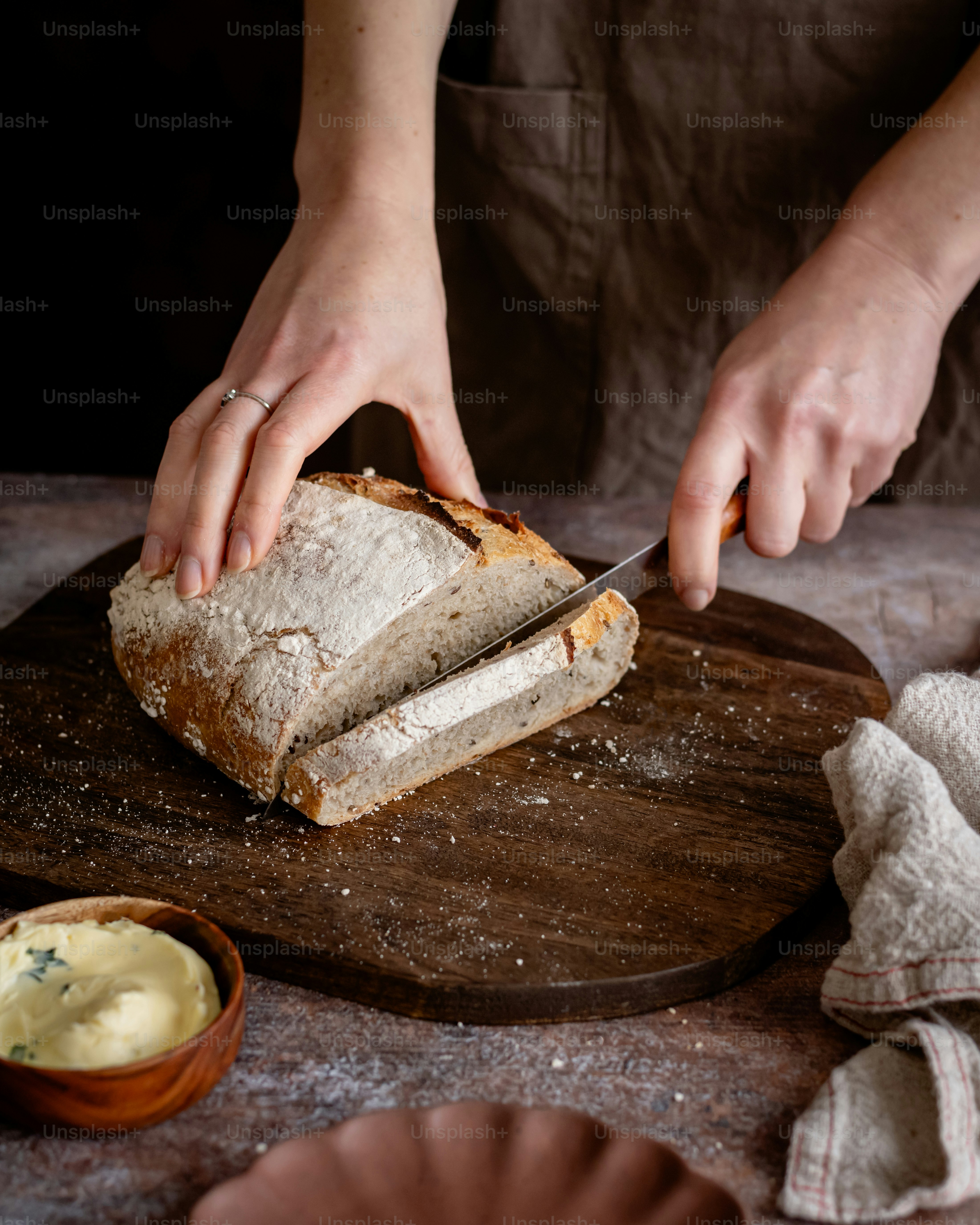 a person cutting a loaf of bread with a knife