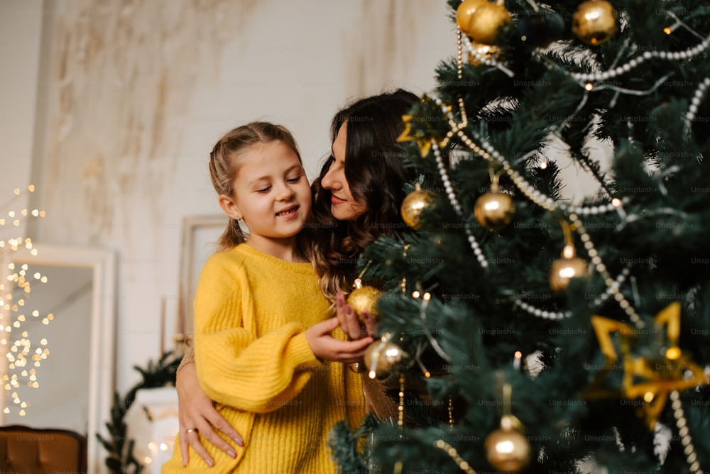 a mother and daughter hugging each other in front of a christmas tree