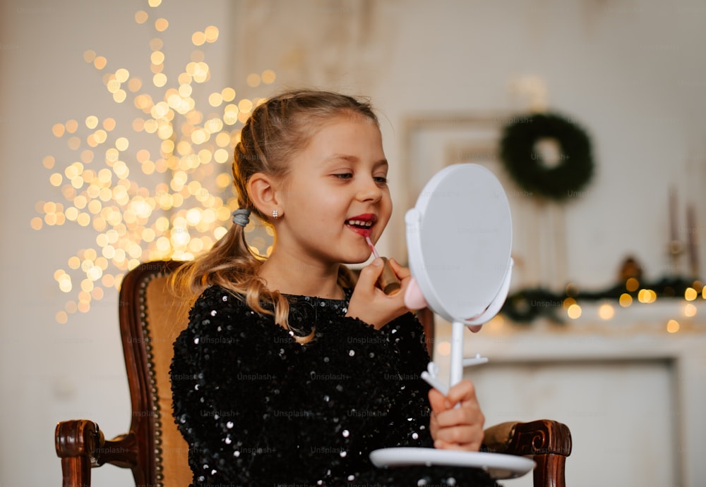 a little girl sitting in a chair holding a mirror