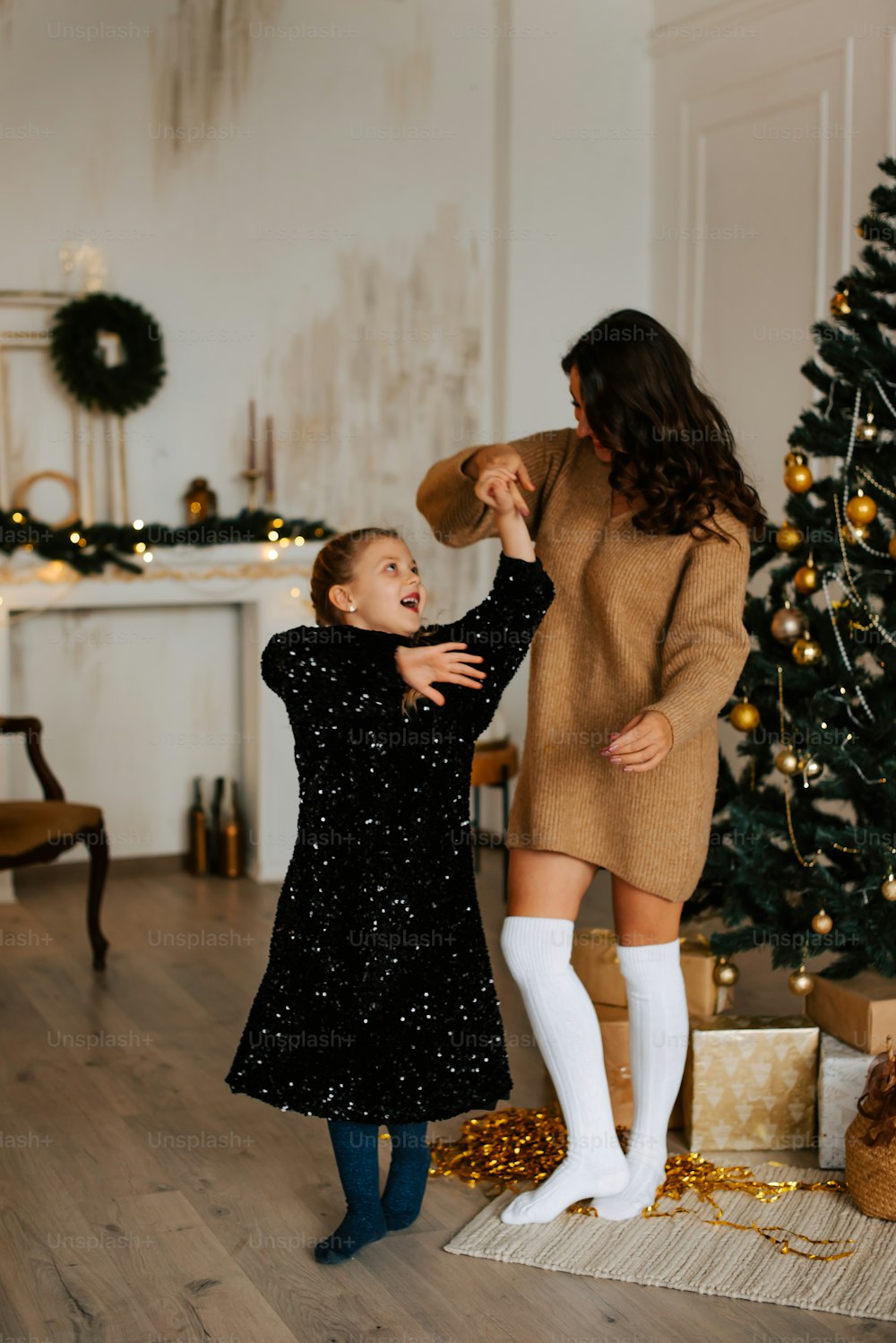 a woman and a little girl standing in front of a christmas tree