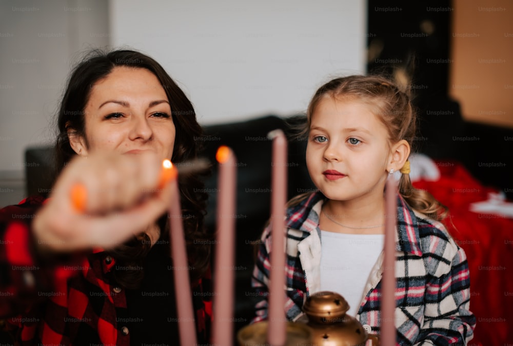 a woman and a little girl sitting at a table with candles