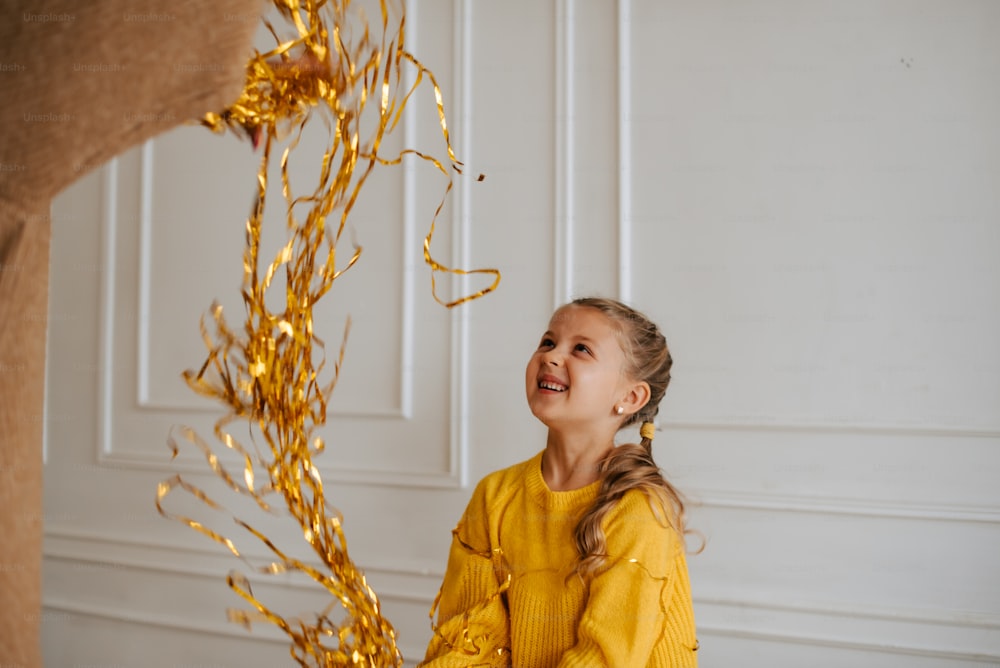 a young girl smiles as she holds a streamer of gold streamers