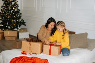a woman and a little girl sitting on a bed with presents