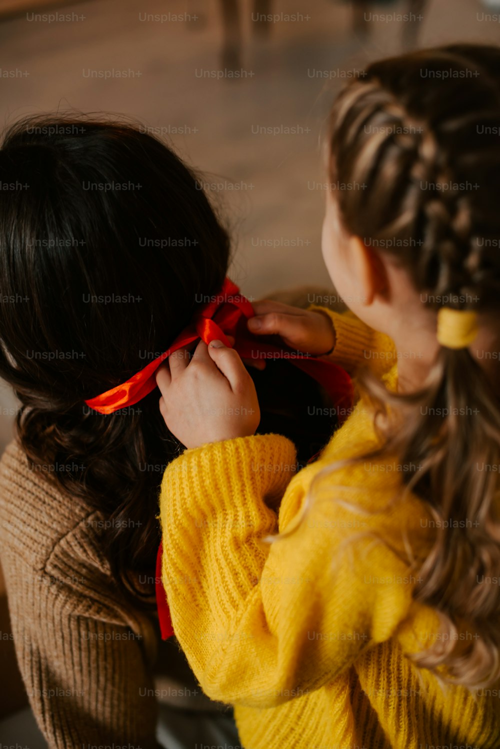 two young girls wearing yellow sweaters and red bow ties