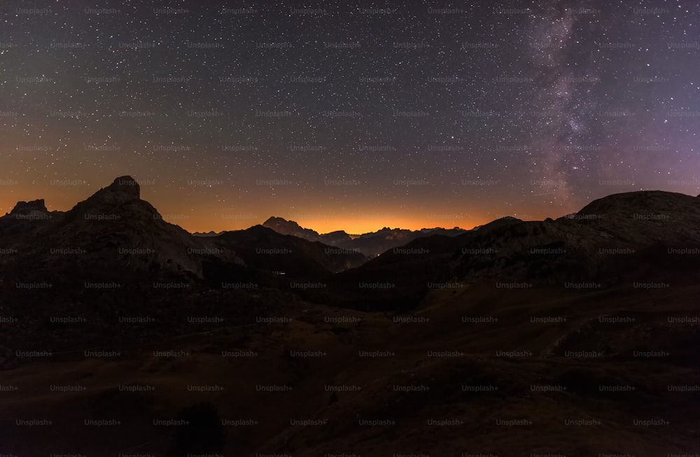 the night sky with stars above mountains