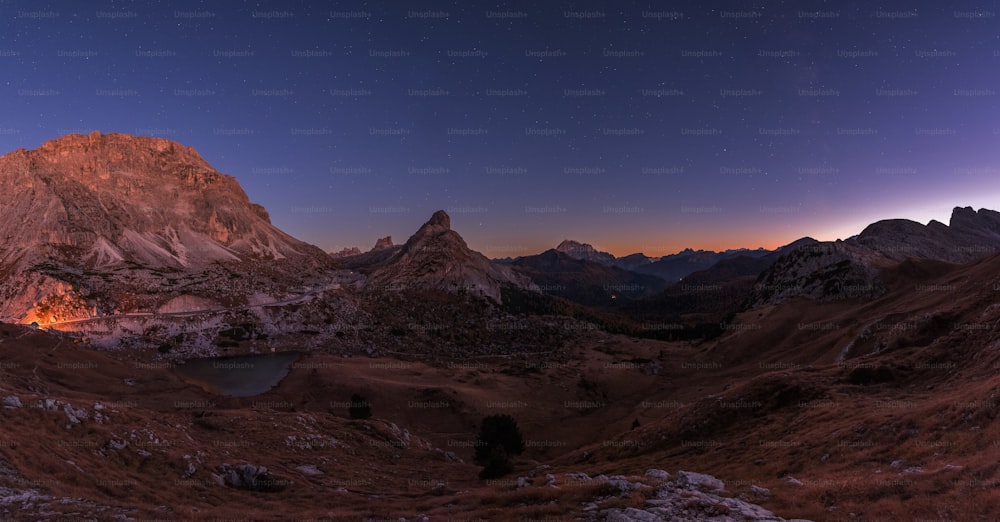a night view of a mountain range with a lake in the foreground