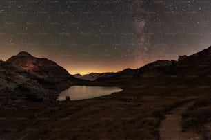 a lake surrounded by mountains under a night sky