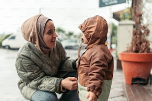 a woman kneeling down next to a little boy