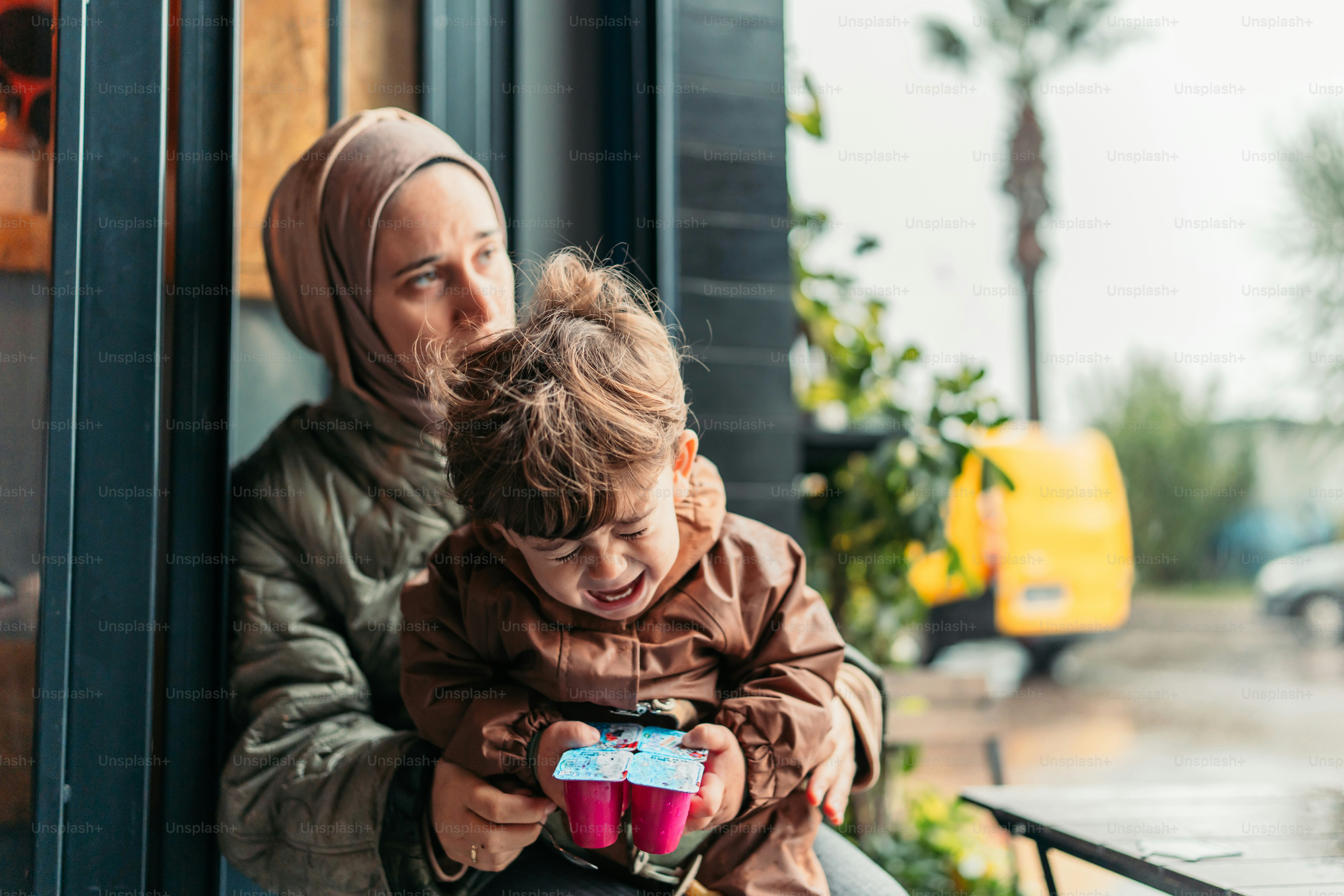 a woman holding a child while looking at a cell phone