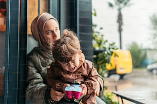 a woman holding a child while looking at a cell phone