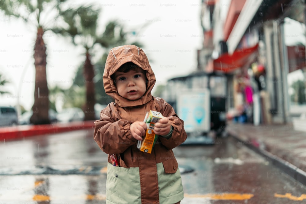 un ragazzino in piedi sotto la pioggia con in mano un ombrello