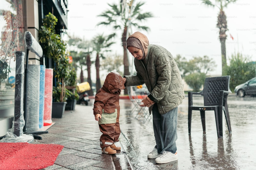 雨の中、小さな男の子の隣に立つ男