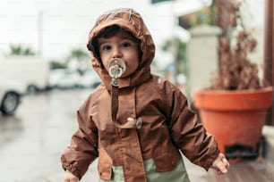 un bambino piccolo che indossa un impermeabile e un ciuccio