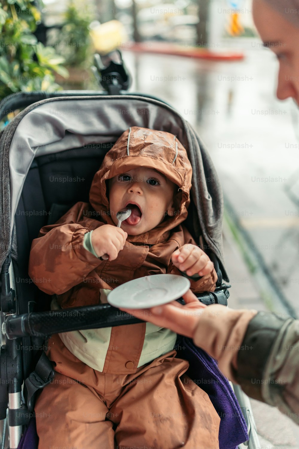 a baby in a stroller being fed a plate