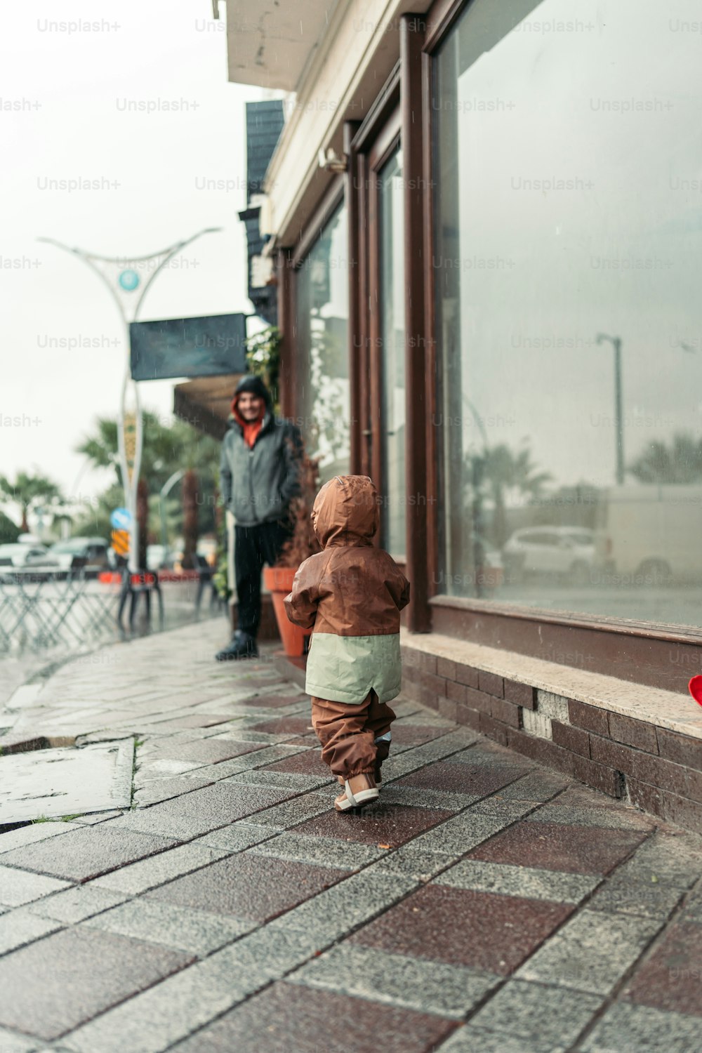 a small child walking down a sidewalk next to a store