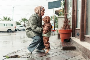 a woman and a child standing on a sidewalk in the rain