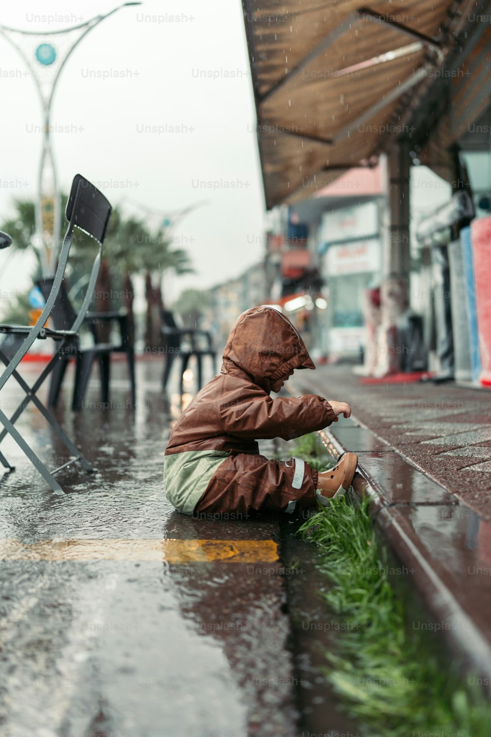 una persona seduta a terra sotto la pioggia