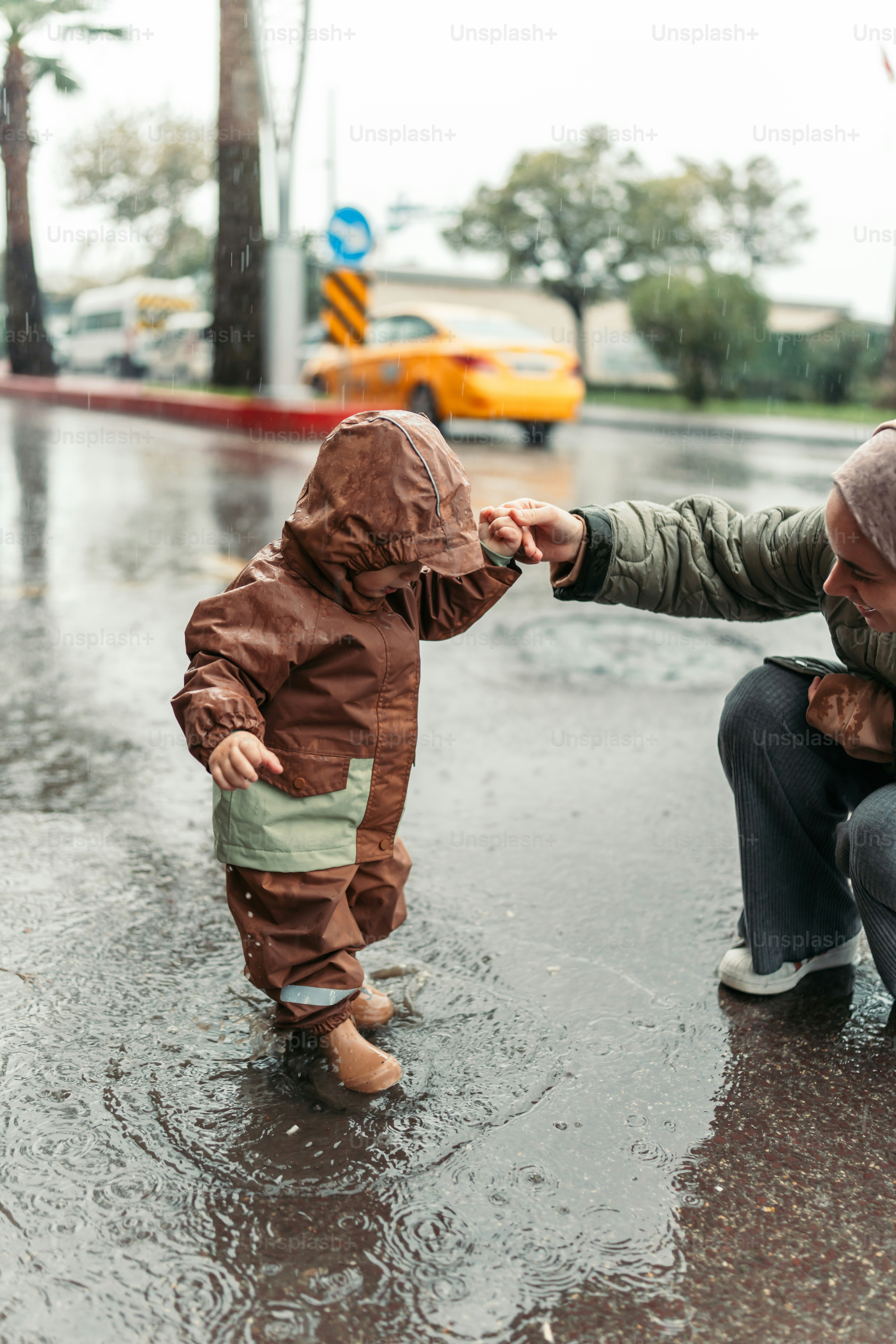 Un homme agenouillé à côté d’un petit garçon sous la pluie