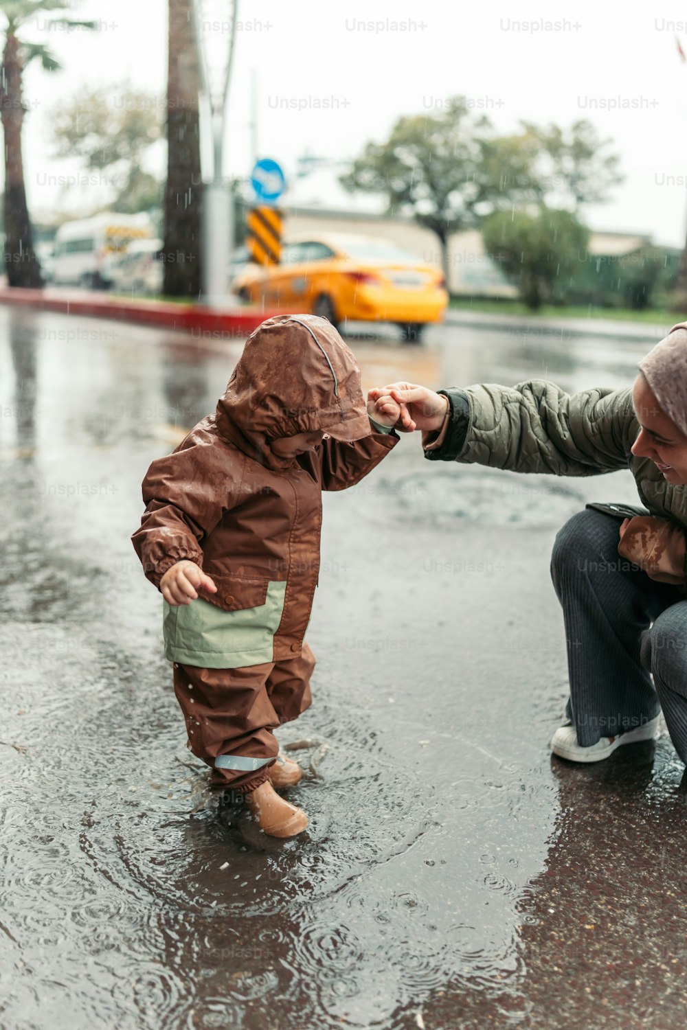 a man kneeling down next to a little boy in the rain