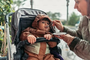 Un bebé en un cochecito siendo alimentado por una mujer