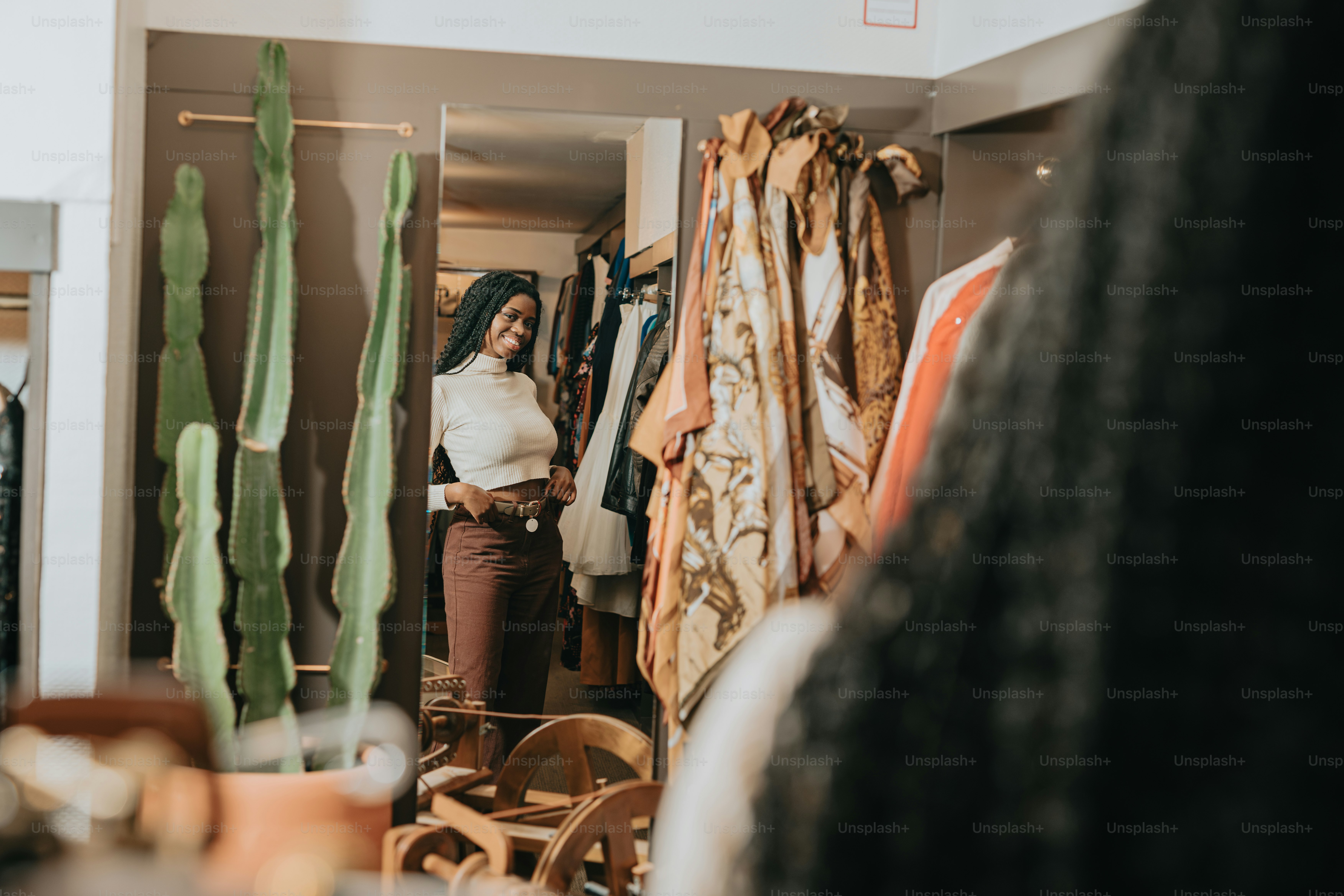 Woman standing in a modern closet next to a potted cactus, browsing clothing options