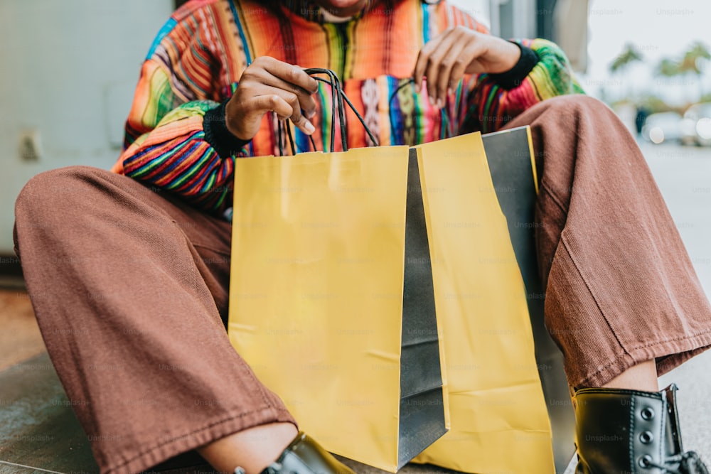 uma mulher sentada no chão segurando um saco de compras amarelo