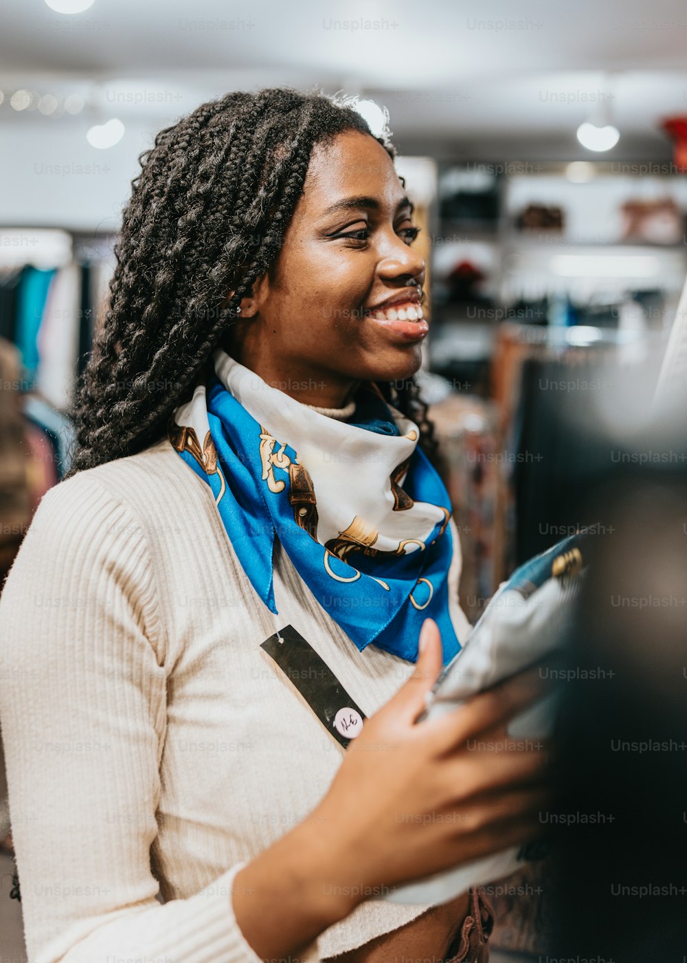 Una donna con i dreadlocks sorride mentre tiene in mano un telefono cellulare