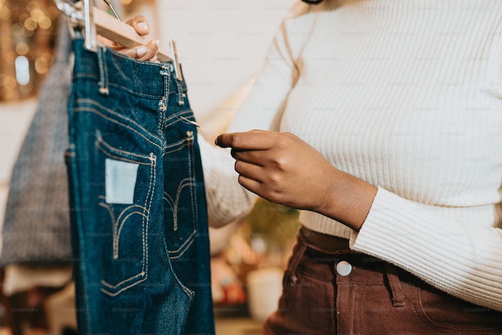 a woman looking at a pair of jeans hanging on a rack