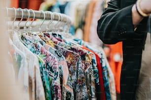 a person standing in front of a rack of shirts