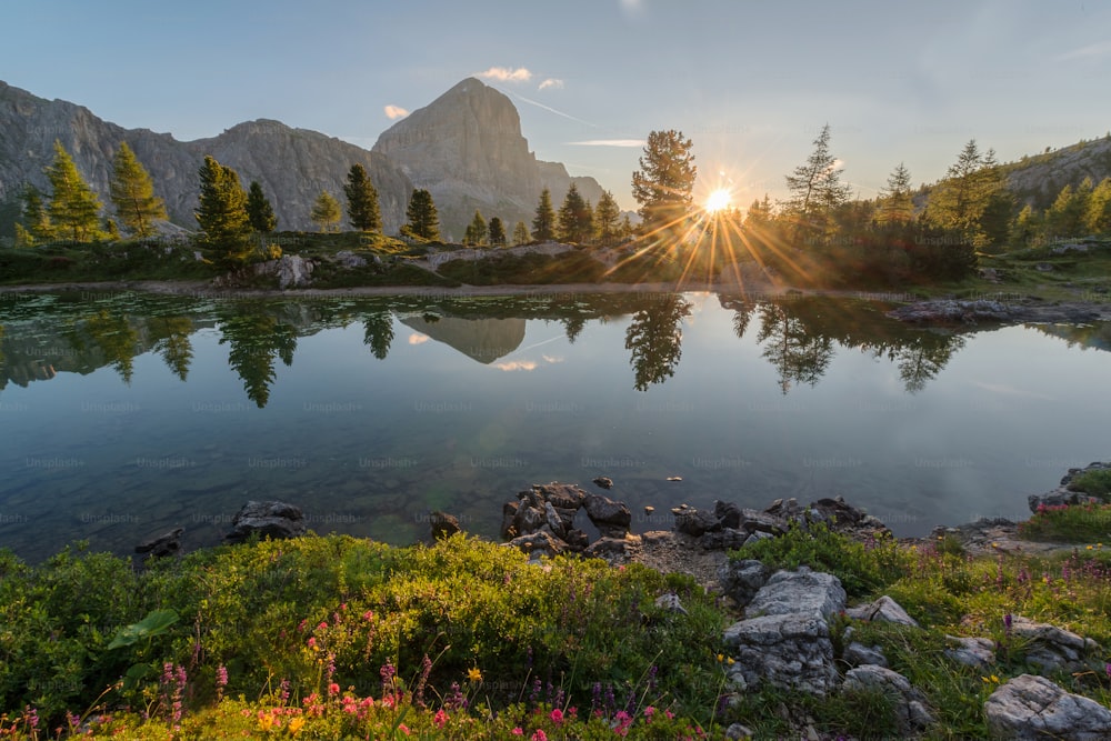 the sun is shining over a mountain lake