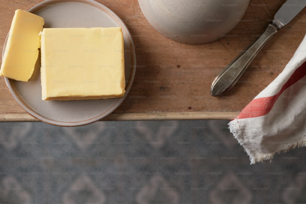 Um pedaço de manteiga fica em um prato ao lado de uma faca de manteiga