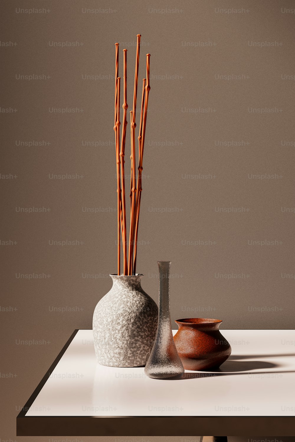 uma mesa branca coberta com dois vasos cheios de varas de bambu